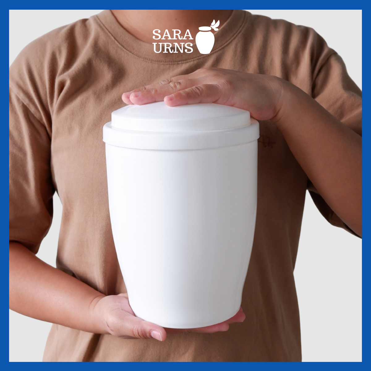 A presentation of a white plastic travel urn held securely by an adult woman with two hands.