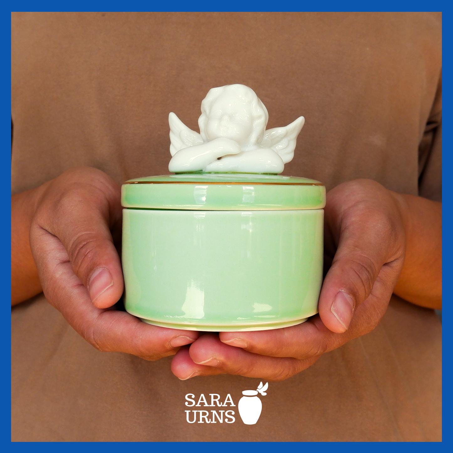 A presentation of a green polished ceramic baby urn held by an adult woman with two hands.