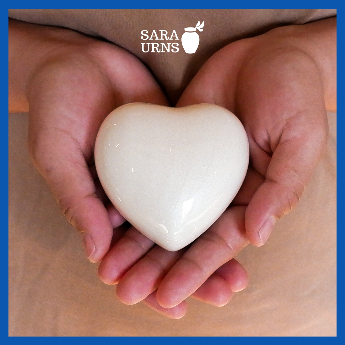 A presentation of a white polished heart-shaped brass metal keepsake urn held by an adult woman with two hands.
