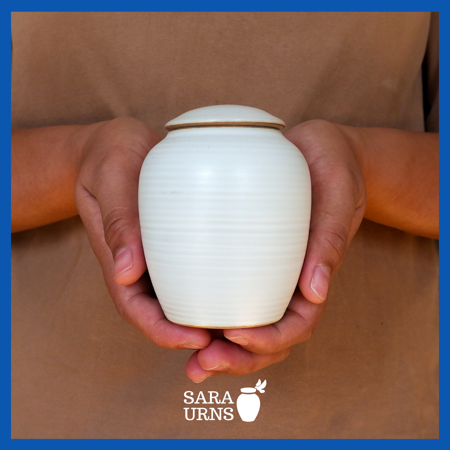 A presentation of a white polished ceramic baby urn held by an adult woman with two hands.