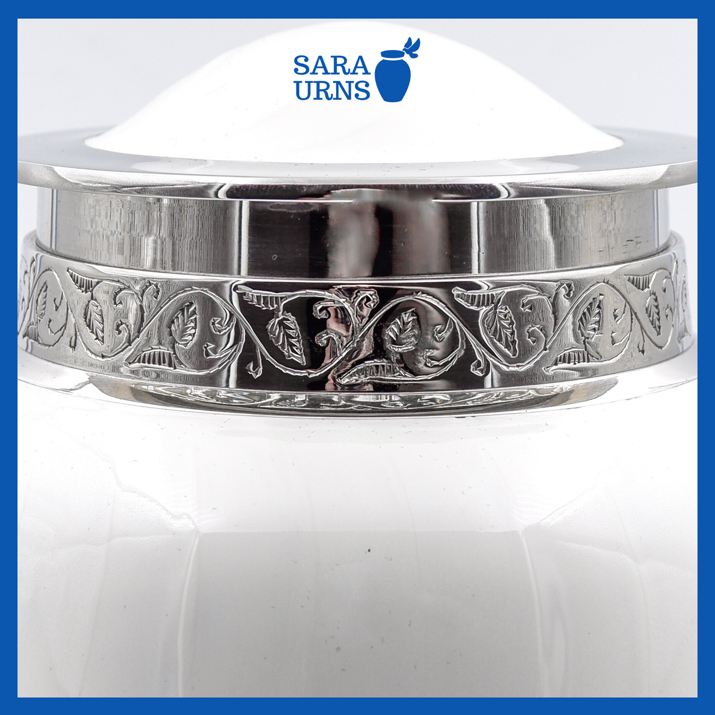 A close-up angle of a white polished brass metal urn which highlights its enamel finish and silver hand-etched details.