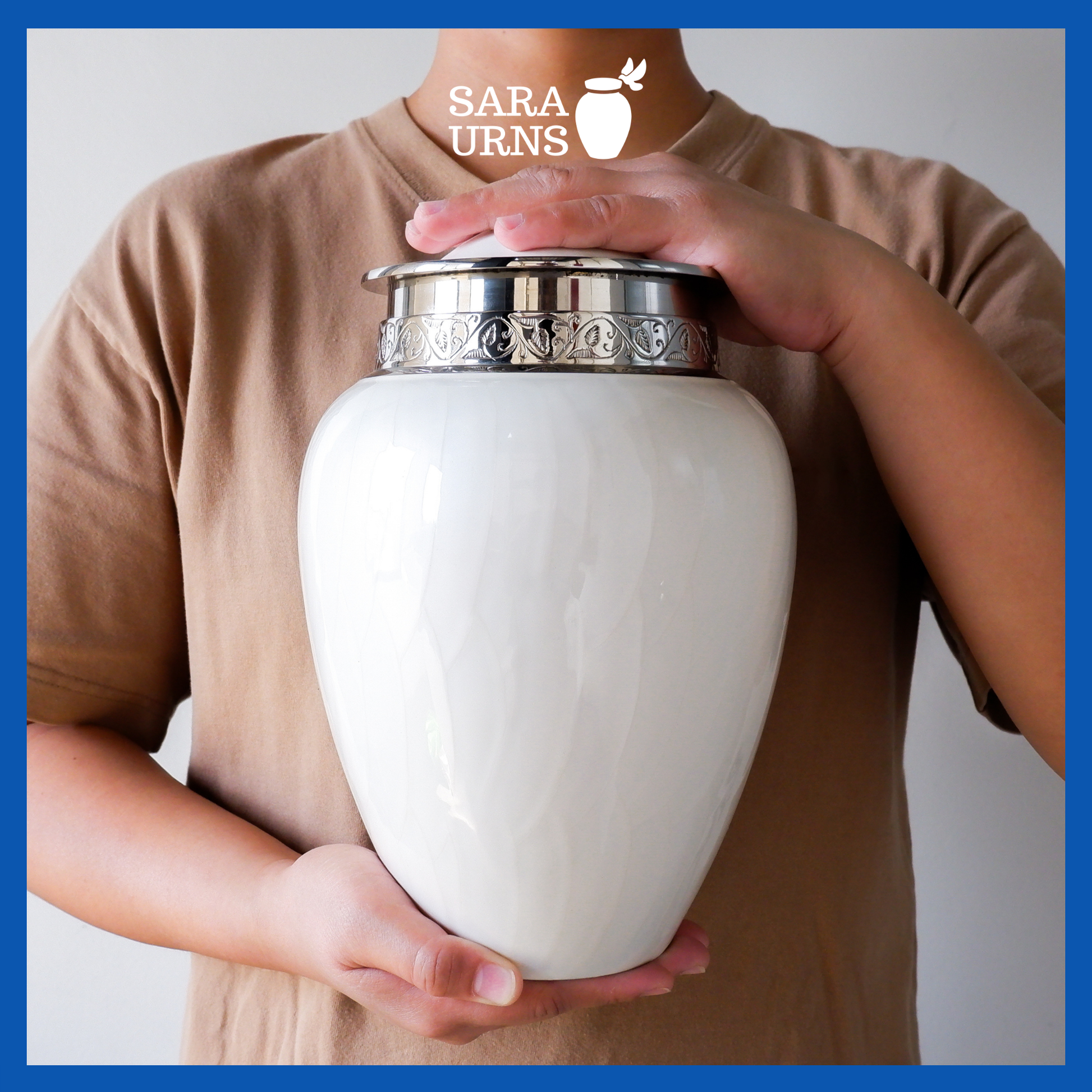 A presentation of a white polished brass metal urn held by an adult woman with two hands.