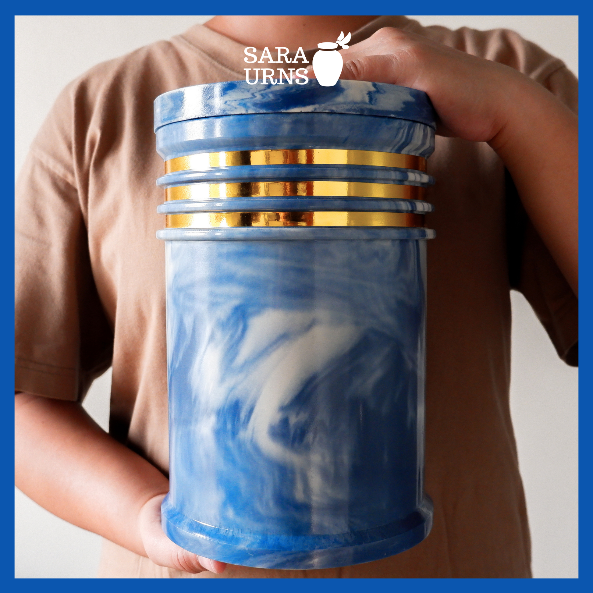 A presentation of a blue cultured marble urn held by an adult woman with two hands.