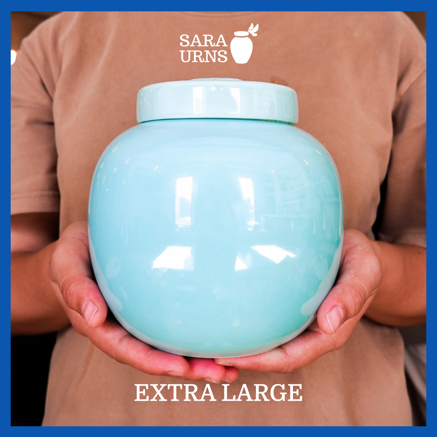 A presentation of an extra large, blue pearly ceramic pet urn held by an adult woman with two palms.