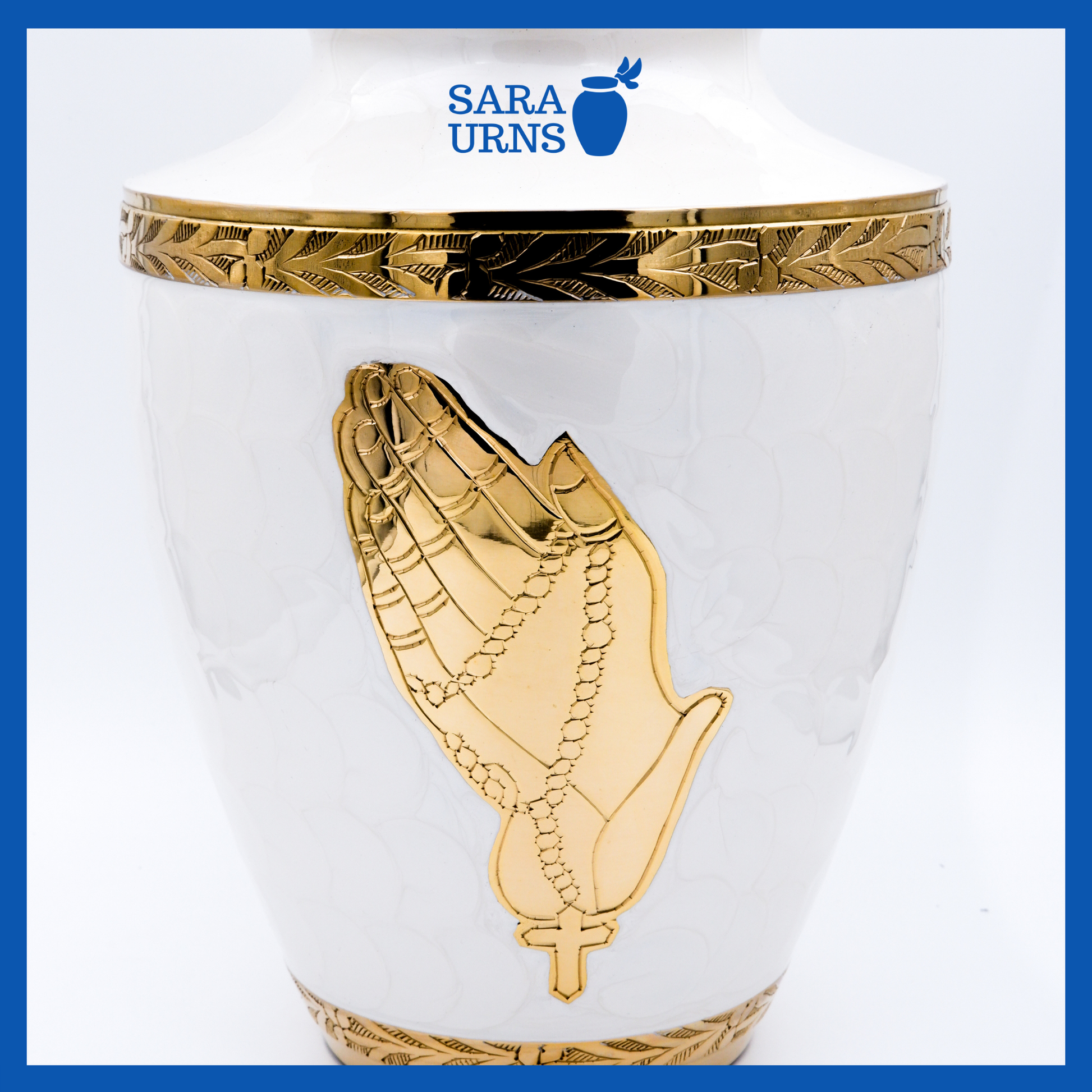 A close-up angle of a white polished brass metal urn which highlights the hand-etched golden praying hands and details.