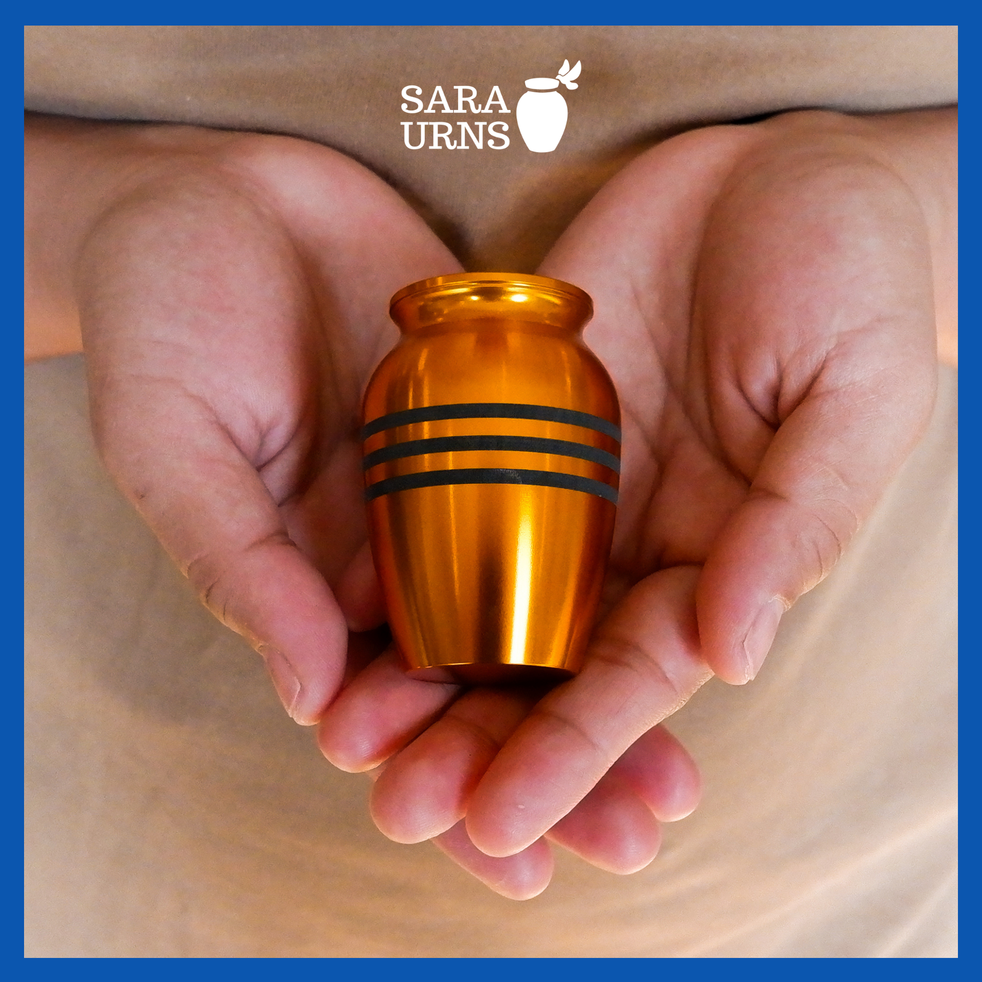 A presentation of a gold alloy metal keepsake urn with three black stripes held by an adult woman with two hands.