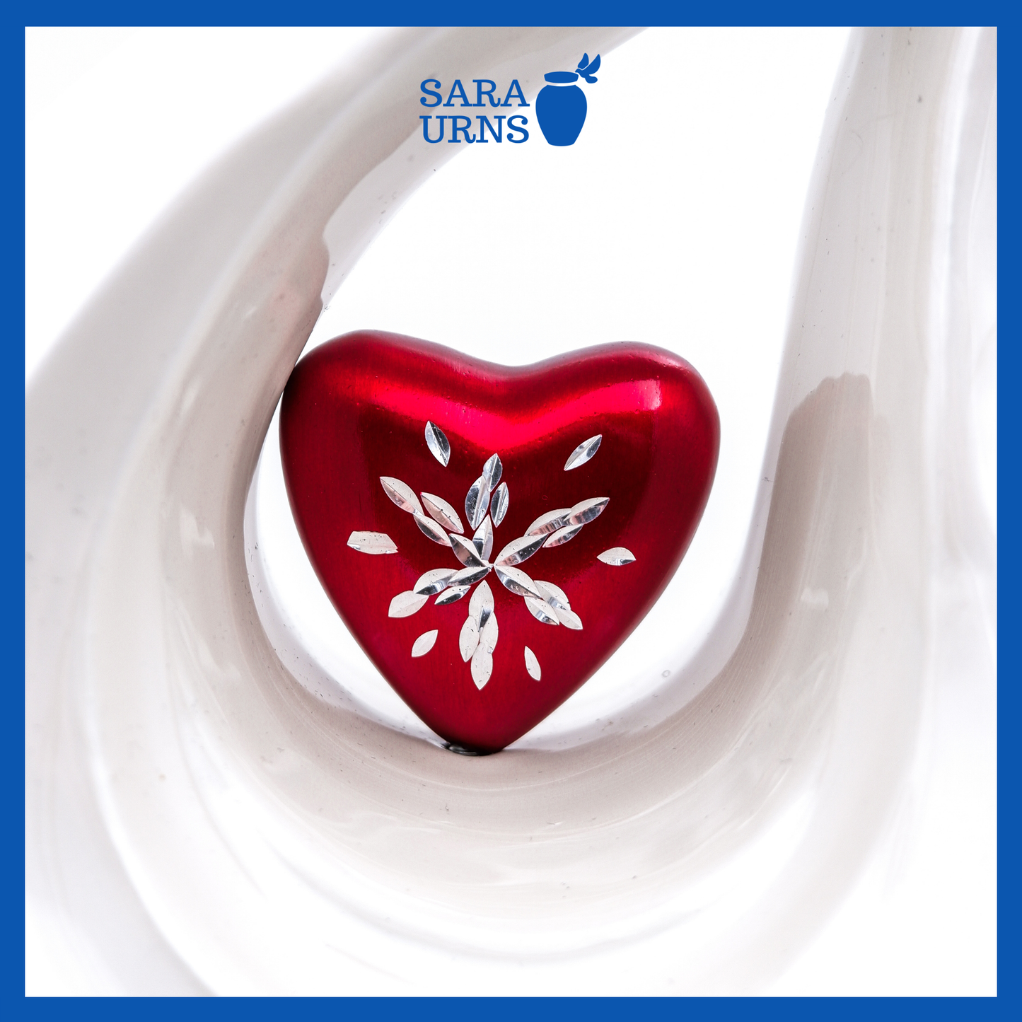 A close-up of a white polished aluminum metal urn with a droplet shape which highlights its heart centerpiece.