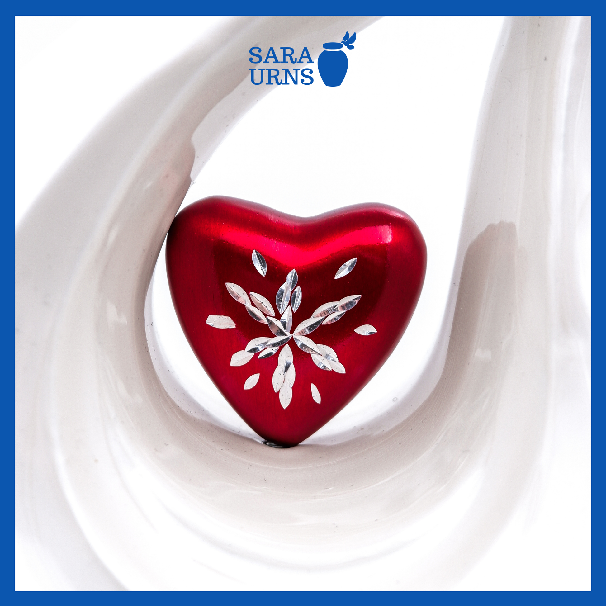 A close-up of a white polished aluminum metal urn with a droplet shape which highlights its heart centerpiece.