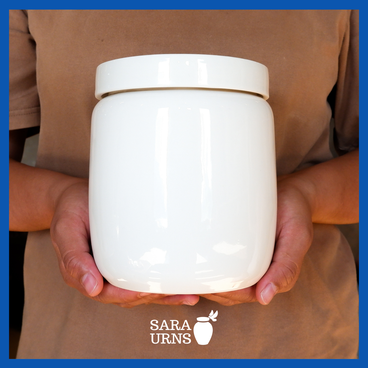 A presentation of a large, all-white polished ceramic baby urn held by an adult woman with two hands.