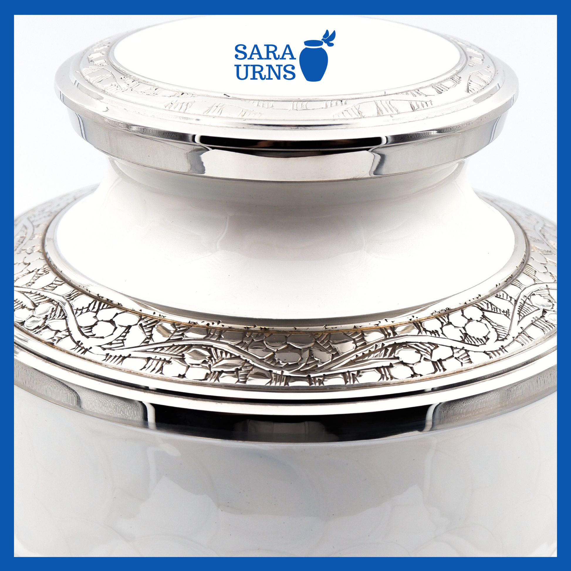 A close-up angle of a white polished brass metal urn with an enamel finish which highlights its silver hand-etched details.