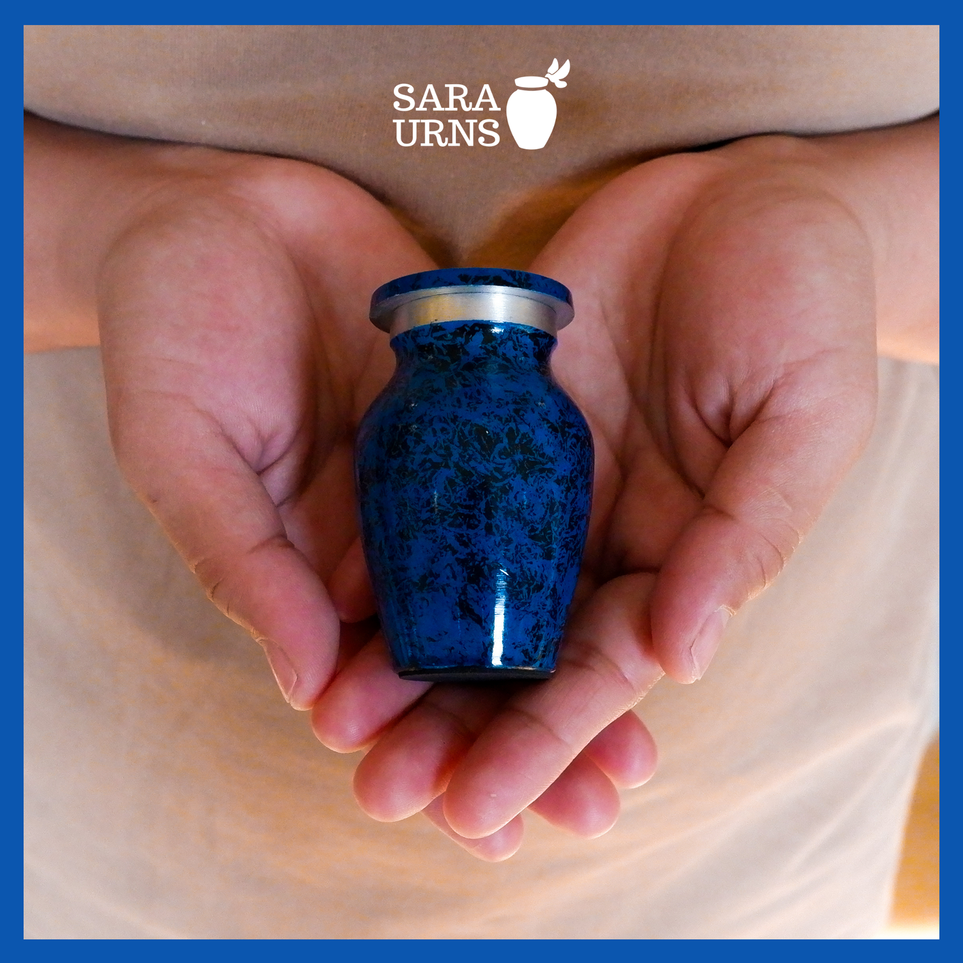 An all-blue aluminum metal keepsake urn with a black speckled pattern across the body and lid held by an adult woman with two hands.