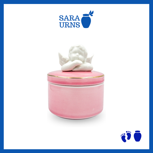 A pink polished ceramic baby urn with a cherub lid over a white background.