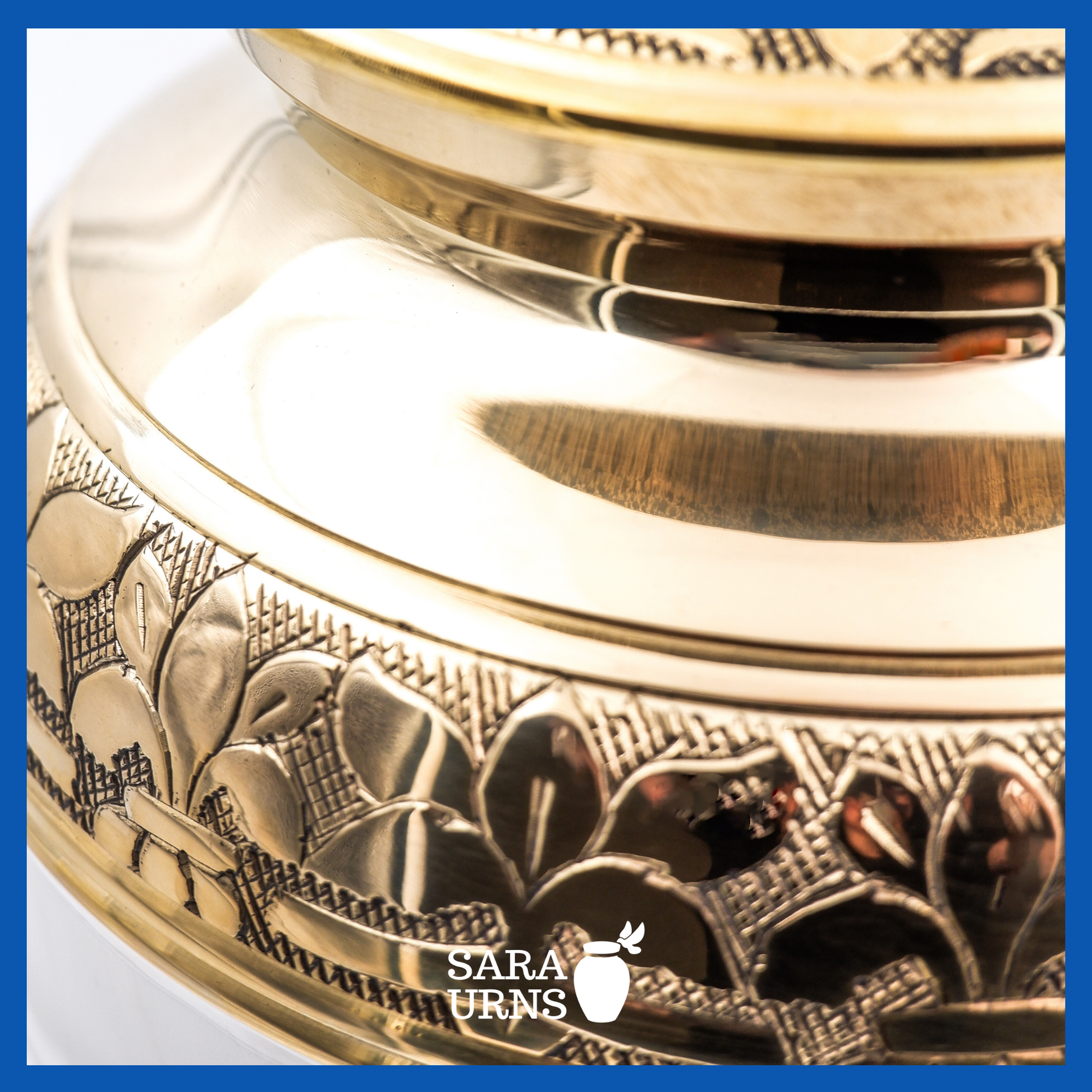 A close-up angle of a white polished brass metal urn which highlights its golden, hand-etched leaf pattern detail.