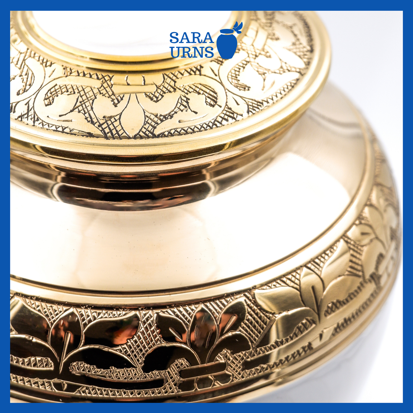 A close-up angle of a white polished brass metal urn which highlights its golden, hand-etched leaf pattern detail.