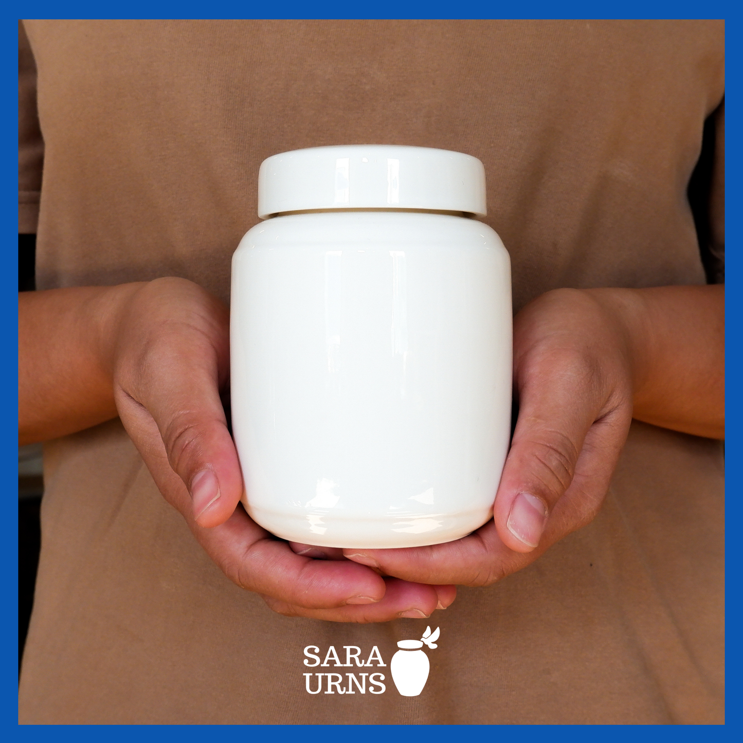 A presentation of an all-white polished ceramic baby urn held by an adult woman with two hands.