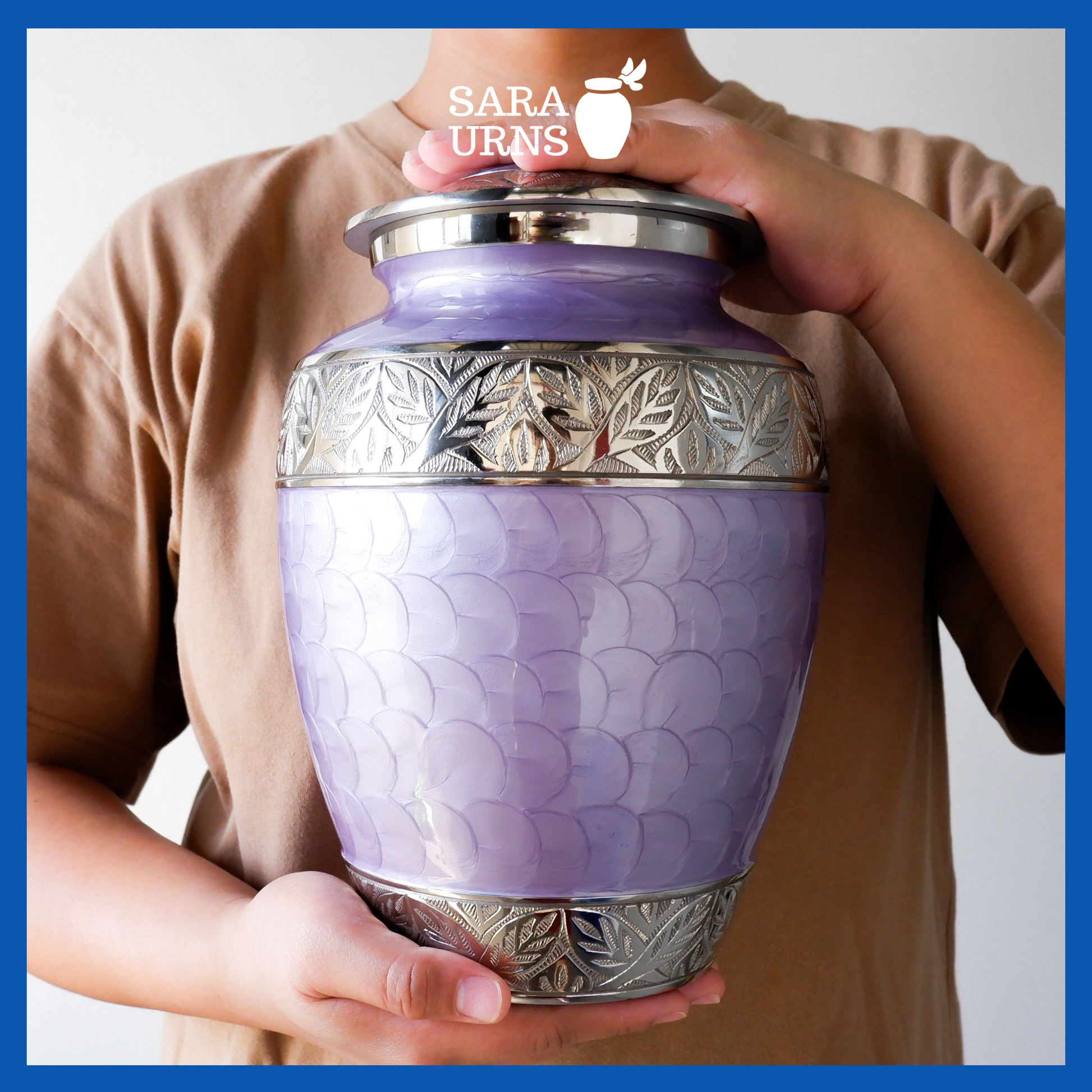 A presentation of a purple polished aluminum brass metal urn with an enamel finish and hand-etched details held by an adult woman with two hands.