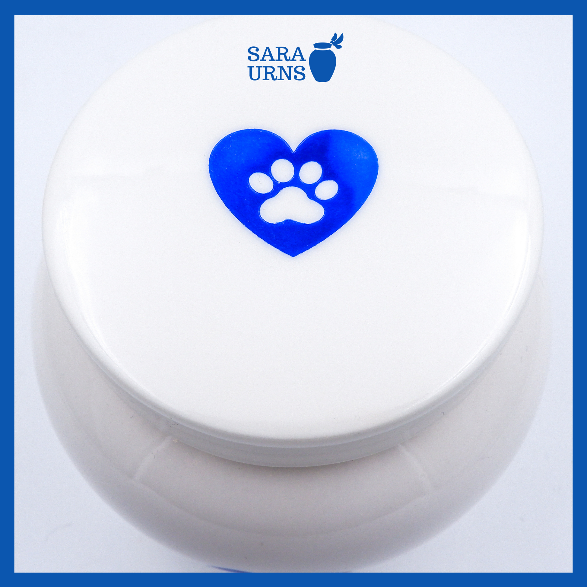 A higher angle of a white polished ceramic pet urn with a blue metallic foiled heart at its center.