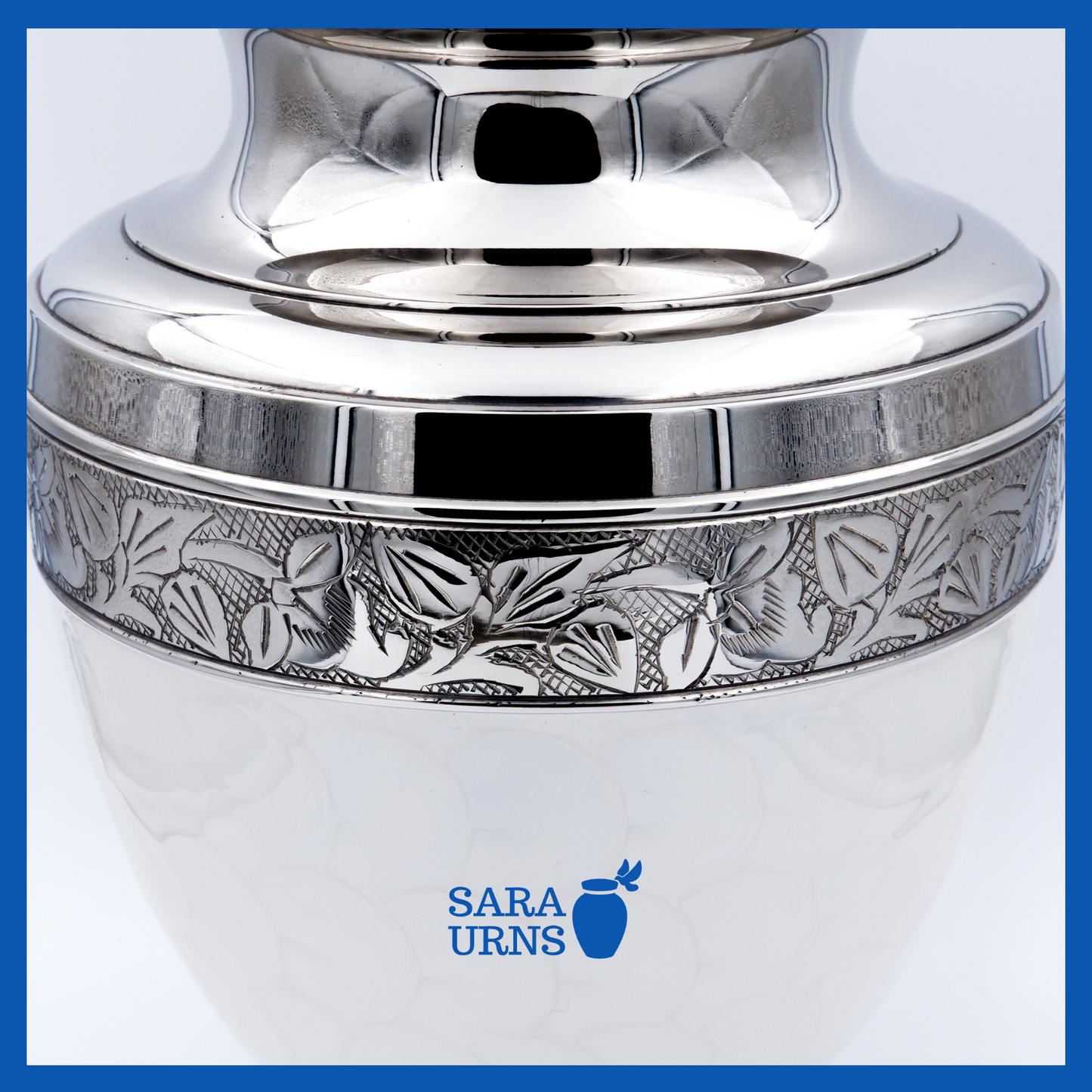 A close-up angle of a white polished brass metal urn which highlights its white enamel finish and silver hand-etched details.