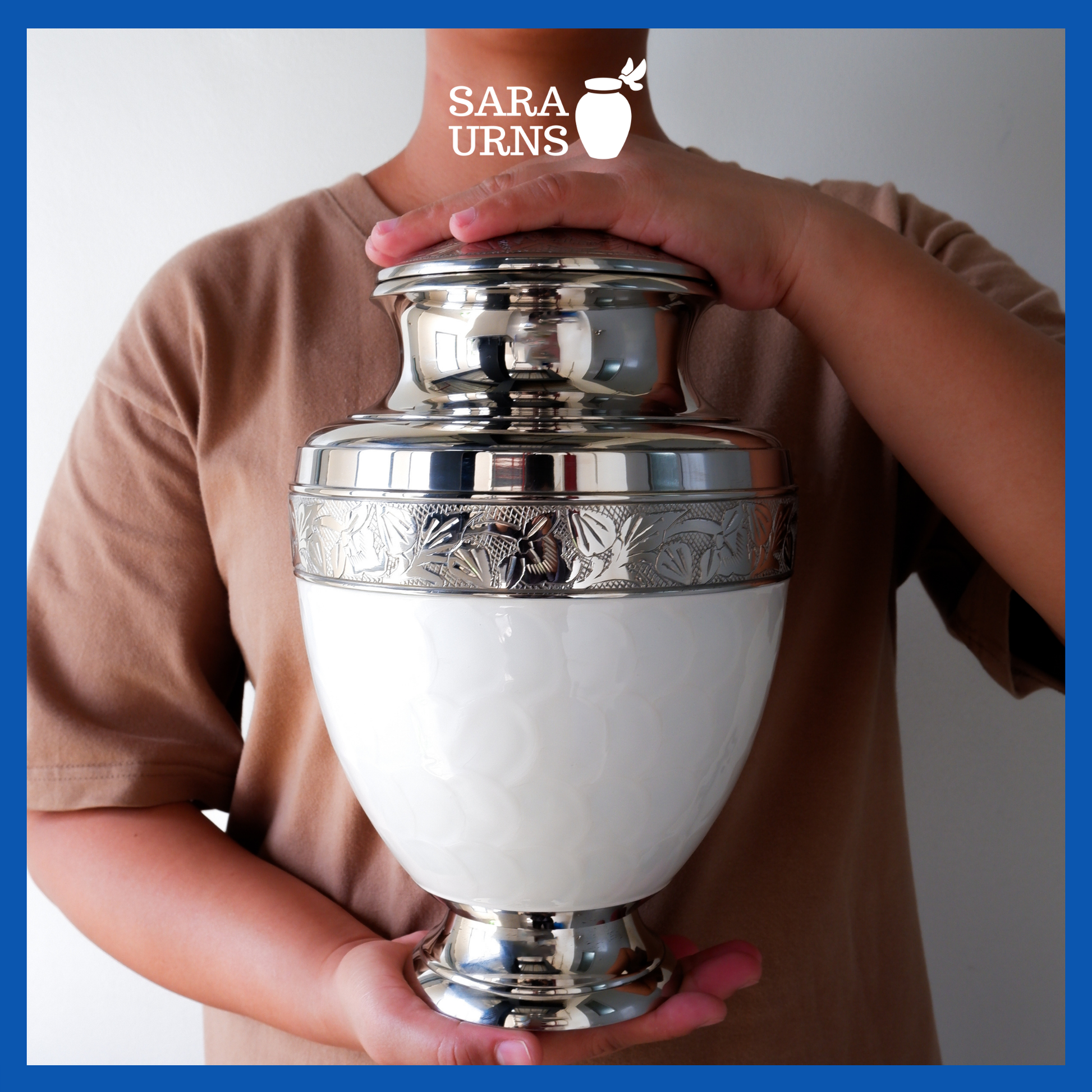 A presentation of a white polished brass metal urn held by an adult woman with two hands.