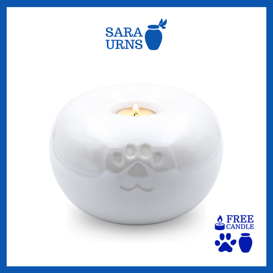 A white ceramic pet urn with a pearly finish with a candleholder feature over a white background.