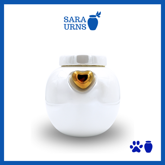 A white ceramic pet urn with a pearly finish, a gold heart at its center and an embossed paw detail in the lid over a white background.